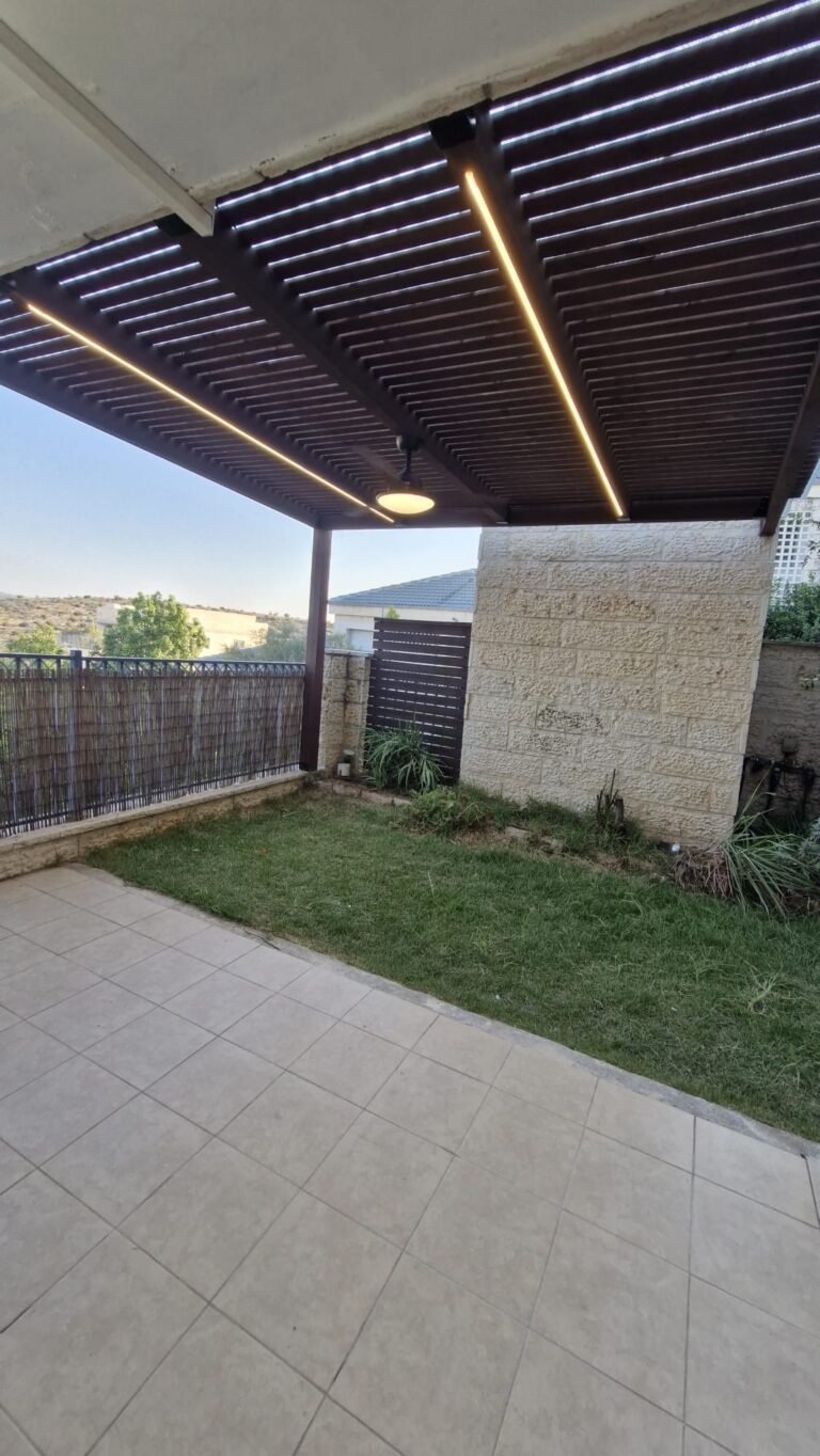 פרגולה כהה עם תאורת לד מעל חצר עם דשא